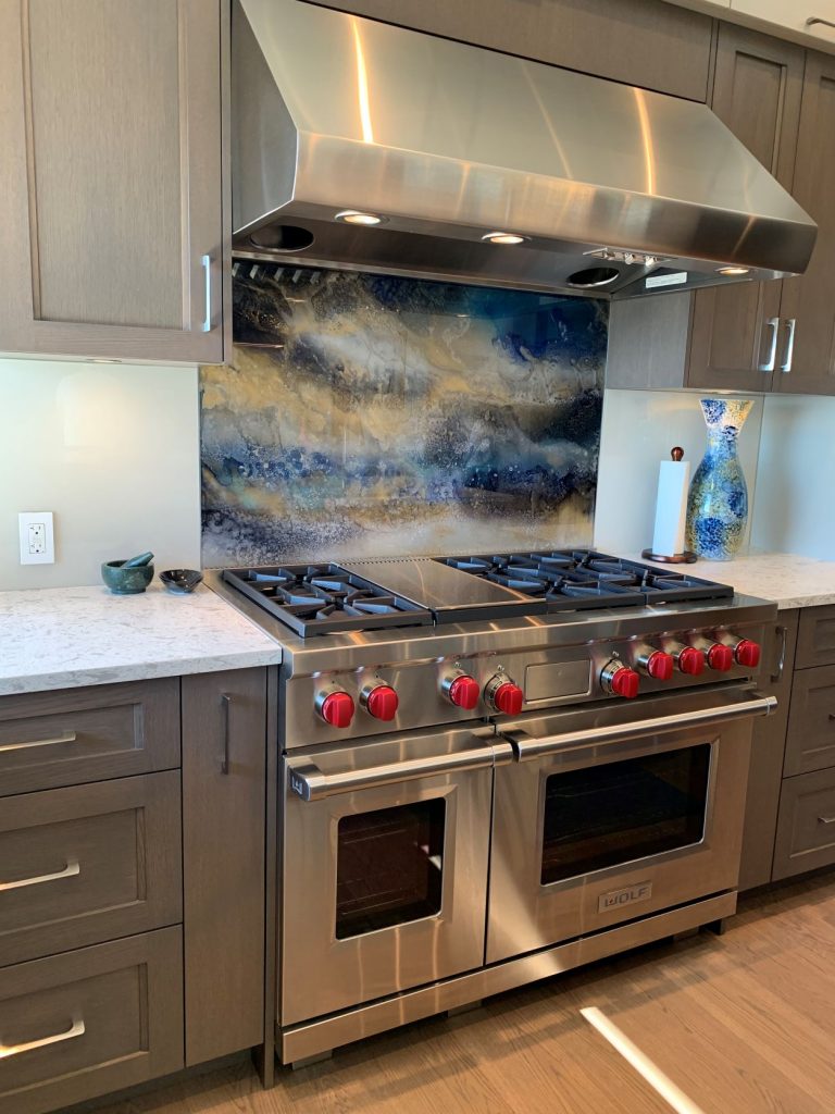 backsplash behind the range is an artistic, one-of-a-kind painted glass by Nikki Design Studio